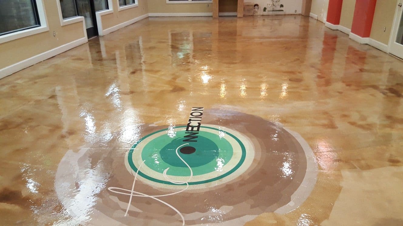 Glossy stained concrete floor with a circular logo design in a spacious interior setting.