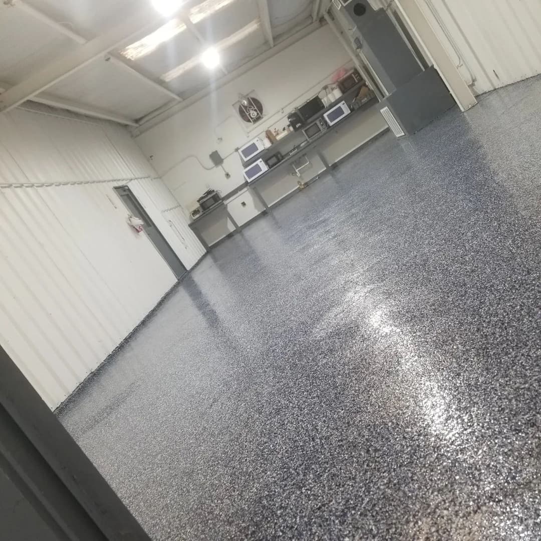 Shiny epoxy floor in a spacious industrial garage with overhead lights and appliances.