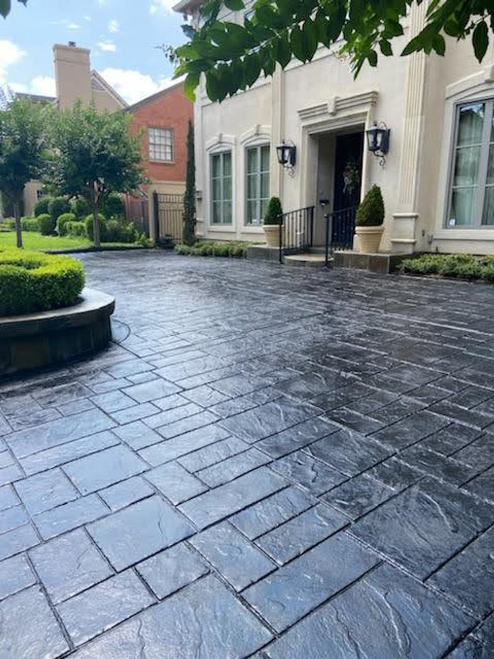 Elegant home entrance with stylish stamped concrete driveway and manicured landscaping.