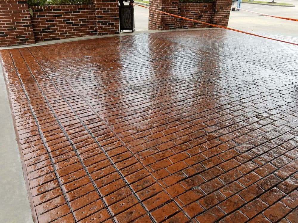 Freshly sealed decorative stamped concrete patio with a glossy finish and wet surface.